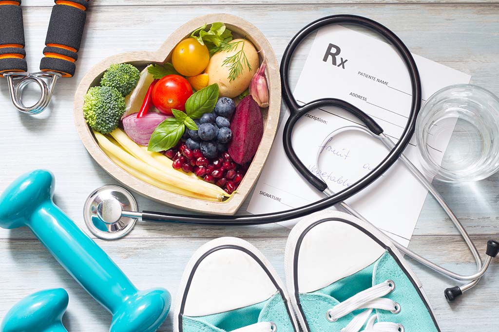 a dish of vegetables next to dumbbells and a prescription