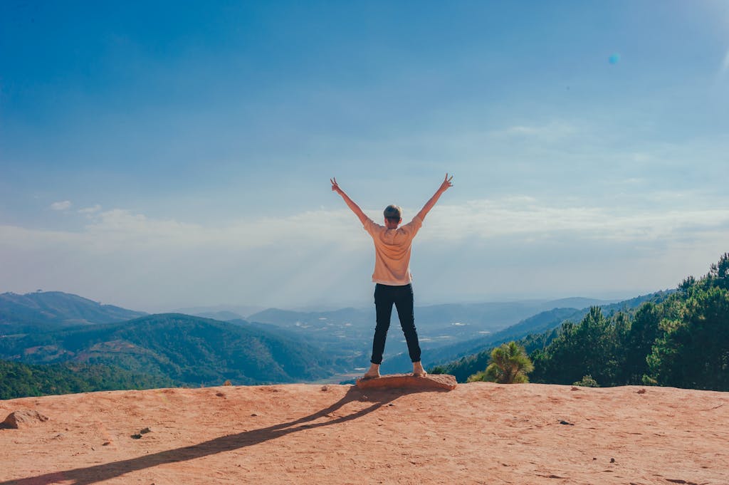 Woman Standing on Cliff with arms raised in triumph