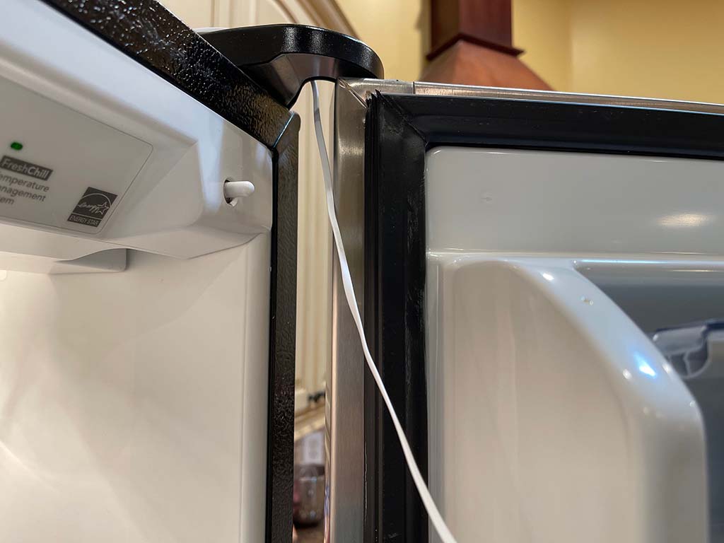 Flat cord of Mocreo ST5 temperature sensor threaded through a refrigerator door